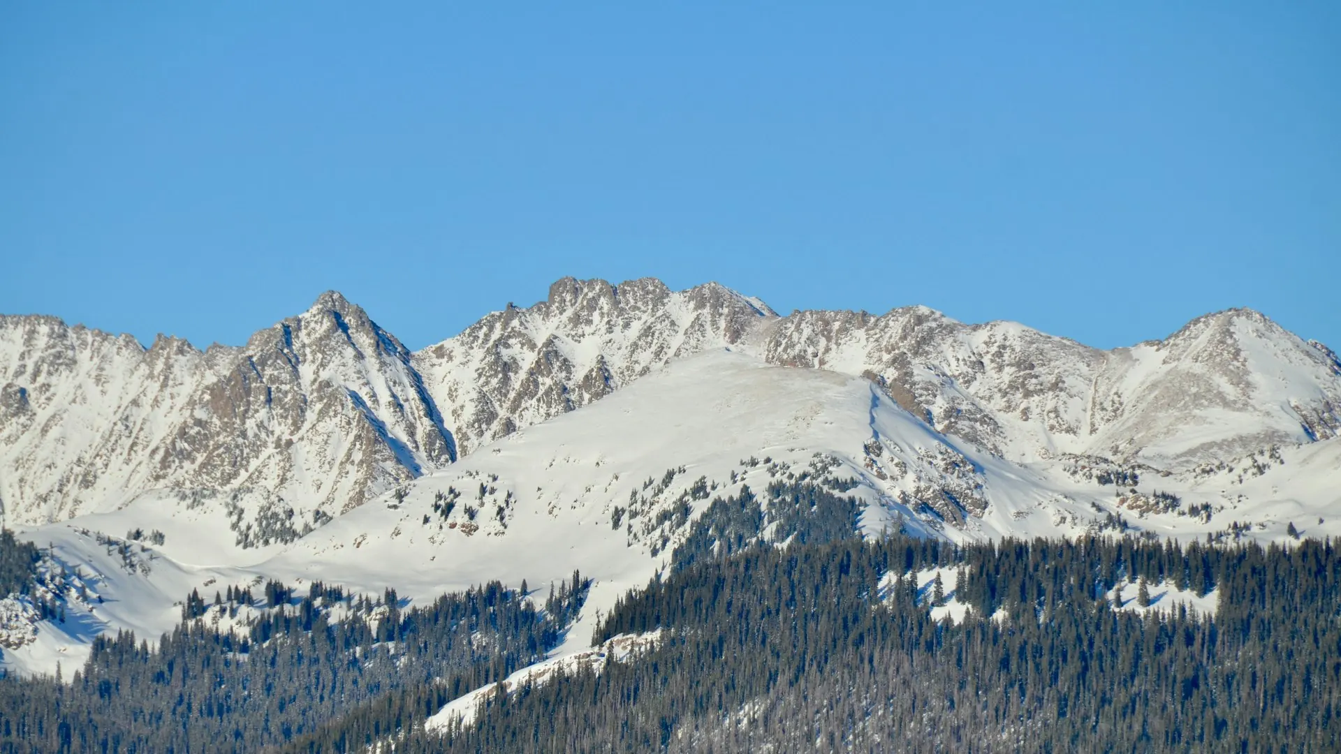 Snow-capped Rocky Mountain peaks under a blue sky